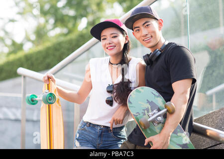 Portrait von fröhlichen jungen chinesischen Paar mit Skateboard Stockfoto