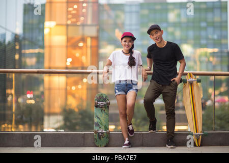 Portrait von fröhlichen jungen chinesischen Paar mit Skateboard Stockfoto