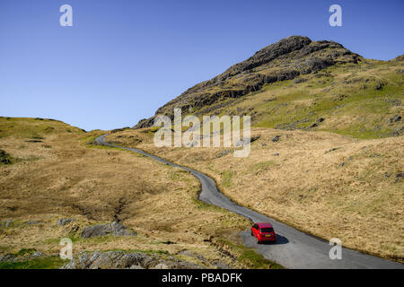 Rotes Auto die steile Straße von Honister, Nationalpark Lake District, Cumbria, England Großbritannien Stockfoto