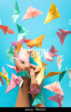 Psychische Gesundheit Konzept. Bunte Papier Schmetterlinge fliegen und sitzen auf womans Hände. Harmonie Emotion. Origami. Papier schneiden Stil. Stockfoto