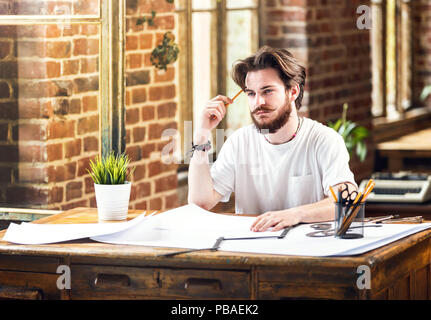 Männliche Architekt mit Bleistift und Entwürfe studieren Pläne im Loft office Bärtigen Stockfoto