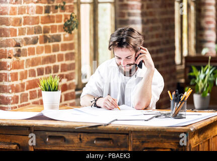 Ehrfürchtige männliche Architekt mit Bleistifte und Blueprint mit Handy im Loft office Bärtigen Stockfoto