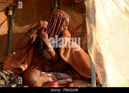 Frau Himba Anwendung Otjize (eine Mischung aus Butter, Ocker und Asche) zu Ihrem Haar. Marienfluss Tal. Kaokoveld, Namibia Oktober 2015 Stockfoto