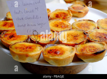 Mini Lemon Quark/Topfen Torten mit Schokolade gefüttert und verbrannte brauner Zucker im Cinnamon Twist Handwerker Bäckerei in Helmsley, North Yorkshire Stockfoto