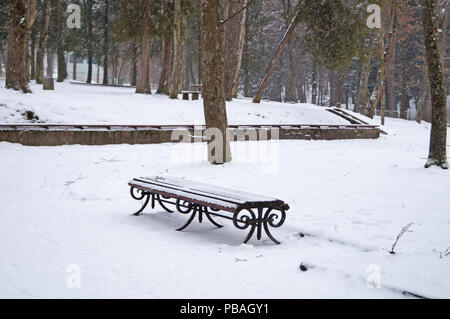 Eine Bank in einem Winter Park mit Schnee an einem Wintertag abgedeckt Stockfoto