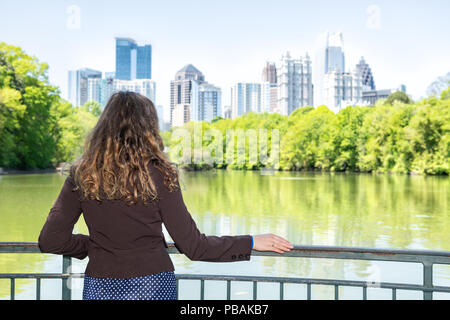 Junge Frau in Piedmont Park in Atlanta, Georgia in der Landschaft, Wasser suchen, und Stadtbild Skyline der Stadt Wolkenkratzer im Stadtzentrum, See Cl Stockfoto