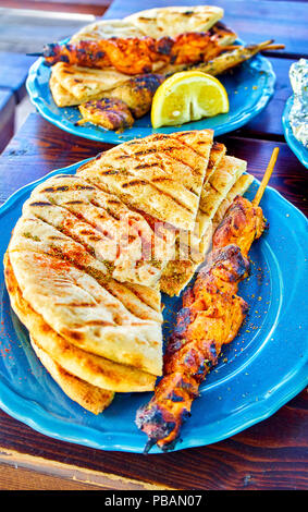 Gewürzte Huhn Souvlakis mit erfahrenen Fladenbrot, und Pilz Souvlaki im Hintergrund. Typische griechische Spieß. Stockfoto