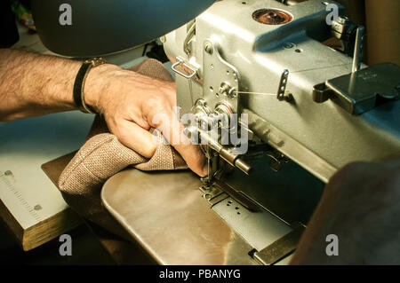 Leder mann Hände maßgeschneiderte, Leder Tasche von Nähmaschine closeup als Szene des Arbeitsprozesses Stockfoto