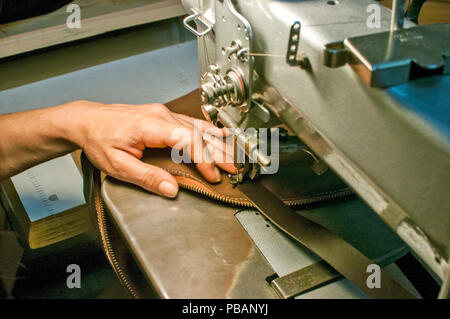 Weibliche Hände der Näherin, Leder Tasche von Nähmaschine closeup als Szene des Arbeitsprozesses Stockfoto