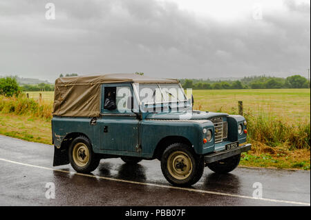 Alte 1967 Series II Land Rover Antriebe entlang einer Landstraße in der Nähe von Dunmanway, West Cork, Irland an einem regnerischen Tag mit Kopieren. Stockfoto