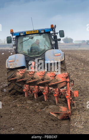 Das pflügen ein Feld mit einem New Holland T7030 und 5 Furche reversible Kuhn Pflug, entfernt. North Yorkshire, UK. Stockfoto