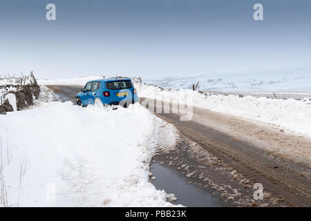 Auto verlassen in einer schneeverwehung auf einer Landstraße in Cumbria, nach einem Schneesturm. Stockfoto