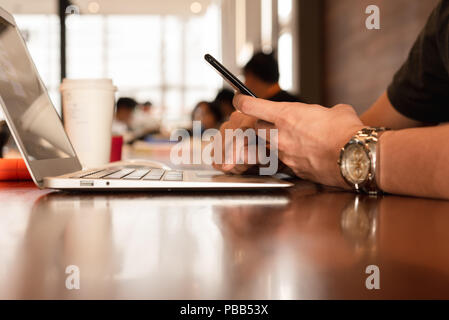 Der Menschen Hand Smartphone und Laptop Stockfoto