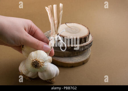 Hand, die Knoblauchzehen in Aussicht auf einen hölzernen Textur Stockfoto