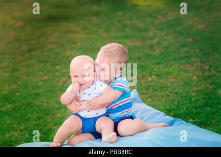 Glückliche zwei kleine Brüder spielen auf dem Rasen Stockfoto