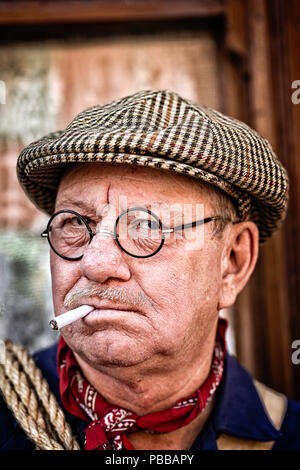 Nahaufnahme, Ansicht von vorne Portrait von kriegszeiten re-Enactor, in Gläser & Suche ernst, mit Tweed flacher Deckel & Zigarette im Mund. Arthur Lowe, der identisch ist. Stockfoto