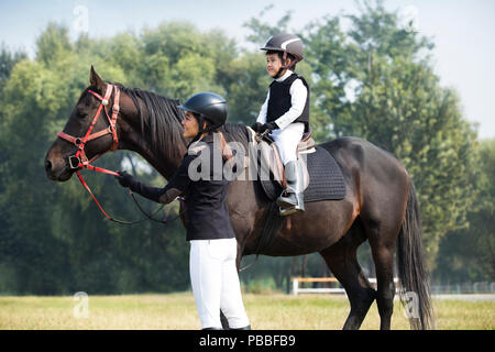 Junge chinesische Mutter lehre Tochter Reiten Stockfoto