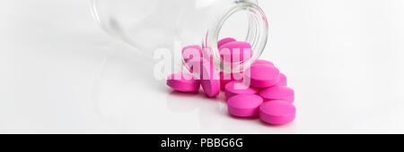 Mehrere große Helle rosa Tabletten gegossen aus Glas auf einer glänzenden weißen Hintergrund. Stockfoto