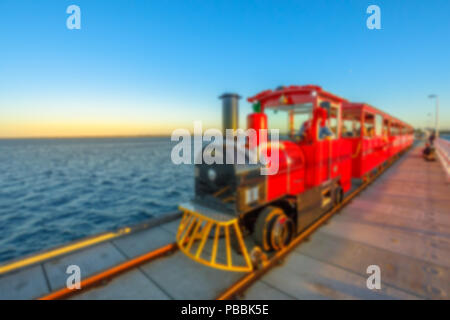 Defokussiertem Hintergrund mit Vintage Red Train auf hölzernen Steg. Wahrzeichen in Busselton, Western Australia, in der Dämmerung. Absichtlich verschwommene Post Stockfoto