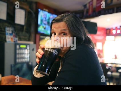 Ältere Frau Getränke ein Pint Guinness in einem irischen Pub. Stockfoto