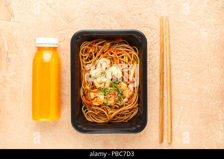 Pasta mit Gemüse und Garnelen in Folie, mit einer Flasche Orangensaft. Gesunde Ernährung, Diät Konzept. Weg für Ernährung. Ansicht von oben Stockfoto