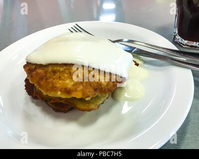 Kartoffelpuffer mit saurer Sahne auf weiße Platte. Studio Foto Stockfoto