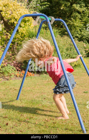 Drei Jahre altes Mädchen turnen Akrobatik auf Apparate, die in der Garten für Spiel, Großbritannien. Stockfoto
