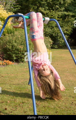 Sechs Jahre altes Mädchen turnen Akrobatik auf Apparate, die in der Garten für Spiel, Großbritannien. Stockfoto