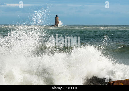 Einzigartige Flut verursacht große Wellen um die Ufer und um einen Stein Leuchtturm in Maine zu brechen. Stockfoto