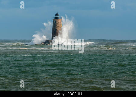 Leistungsstarke seltene Wellen decken einen Stein Lighthouse Tower in Maine. Stockfoto