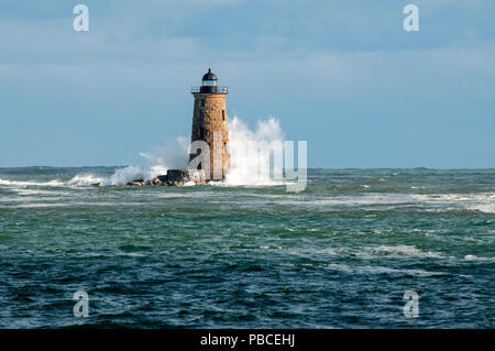 Riesenwellen surround Stein Leuchtturm Turm von Whaleback Licht die Sonne bricht durch die Wolken im Süden von Maine. Stockfoto