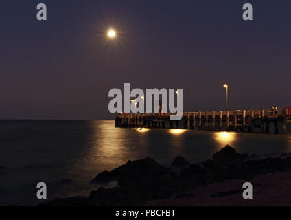 Palm Cove Anlegesteg am Abend, LE kurz nach Sonnenuntergang als der Vollmond steigt Offshore und schafft eine glitzernde Pfad auf dem Wasser Stockfoto