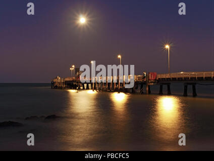 Palm Cove Jetty als Abend wird Nacht LE der Vollmond über den Pier gesetzt und das Hinzufügen Lichteffekte Stockfoto