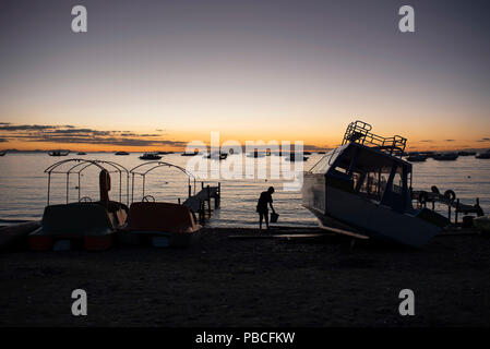Silhouette der junge Fischer, als er an der Fertigstellung der Arbeit am Ende des Tages. Der Titicacasee, Copacabana, Bolivien. Jun 2018 Stockfoto