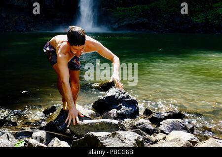 Ein Mann Klettern über Felsen nach dem Schwimmen im eiskalten Oberen Nandroya fällt, fällt Nandroya fällt, Atherton Tablelands, QLD, Australien Stockfoto