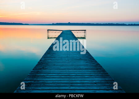 Alte, leere Holzsteg auf See, bei Sonnenaufgang. Stockfoto