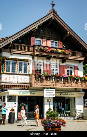 Leute, die vor der traditionellen bayerischen Gebäude im Einkaufsviertel in der Innenstadt von Garmisch-Partenkirchen, Bayern, Deutschland bummeln Stockfoto