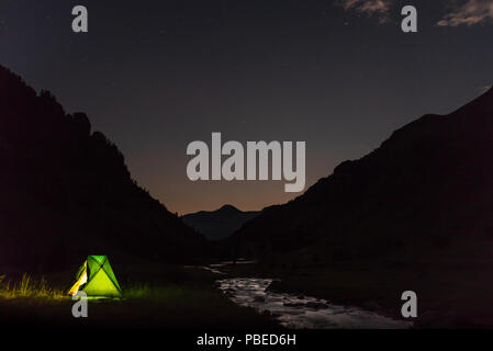 Das Licht scheint durch die Hütte in einer nächtlichen Bergwelt Stockfoto