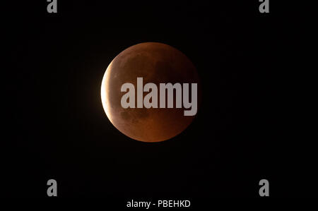 Berlin, Deutschland. 27. Juli, 2018. 27.07.2018, Berlin: Der Mond leuchtet rot, während der totalen Mondfinsternis, während die Dunkelheit langsam abnimmt. Credit: Paul Zinken/dpa/Alamy leben Nachrichten Stockfoto