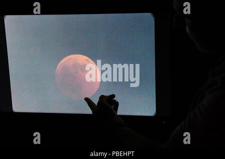 München, Deutschland. 27. Juli, 2018. Der Mond kann in der Sternwarte während die längste Mondfinsternis des 21. Jahrhunderts auf einem Monitor, der den Blick auf ein Teleskop auf den Mond zeigt, betrachtet werden. Credit: Felix Hörhager/dpa/Alamy Leben Nachrichten Quelle: dpa Picture alliance/Alamy leben Nachrichten Stockfoto