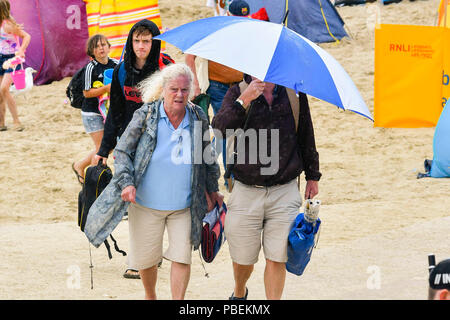 Lyme Regis, Dorset, Großbritannien. 28. Juni 2018. UK Wetter. Urlauber Unterschlupf unter einem Regenschirm verlassen den Strand als der Regen beginnt in den Badeort Lyme Regis am ersten Tag der Hauptversammlung der Stadt RNLI lifeboat Woche an einem kühlen, windigen Tag. Foto: Graham Jagd-/Alamy leben Nachrichten Stockfoto