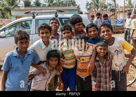 Belathur, Karnataka, Indien - 1. November 2013: eine Gruppe von Jungen in bunten Shirts entlang der Straße schauen und lächeln in die Kamera. Stockfoto