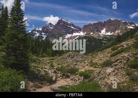 Majestic Maroon Bells Peaks von der rauen Crater Lake Trail gesehen an einem sonnigen Tag mit blauen Himmel im Sommer in der Nähe von Aspen, Colorado Stockfoto