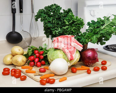 Noch immer leben auf einem Küchentisch Holzbrett, Zutaten für die Suppe: grüne Blätter von Kale, rote und weiße Zwiebel, rötlich, weiße Kartoffeln, Kohl, Toma Stockfoto