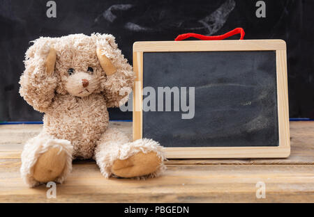 Mobbing in der Schule oder Lernschwierigkeiten Konzept. Teddy Bear mit Ohren und eine leere Tafel, Platz für Text Stockfoto