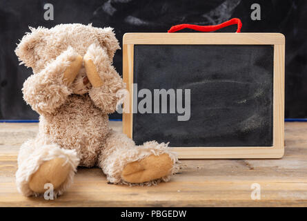 Mobbing in der Schule oder Lernschwierigkeiten Konzept. Teddy Bär für Augen und eine leere Tafel, Platz für Text Stockfoto