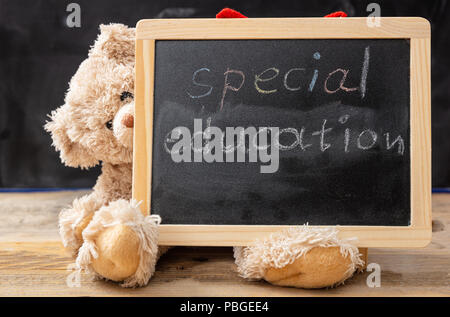 Spezielle Ausbildung. Teddybär hinter einer Tafel versteckt. Special Education text Zeichnung an der Tafel Stockfoto