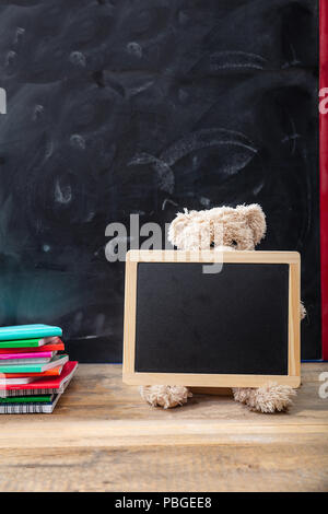 Zurück zu Schule. Teddybär und leere Tafel mit Rahmen auf hölzernen Schreibtisch, Platz für Text Stockfoto