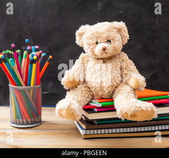 Zurück zu Schule. Teddybär und Bunte Bleistifte und Notebooks auf blackboard Hintergrund Stockfoto