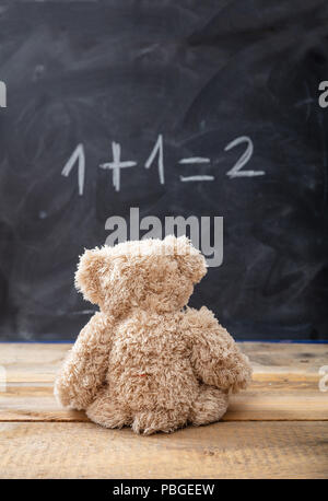 Schule Klasse Math. Teddy Bär auf eine einfache Gleichung auf einer Tafel. Eins plus Eins gleich zwei Stockfoto